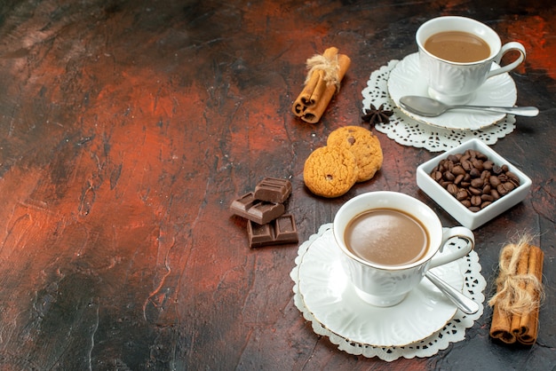 Vista dall'alto di un delizioso caffè in tazze bianche su tovaglioli biscotti cannella lime barrette di cioccolato sul lato sinistro su sfondo a colori misti