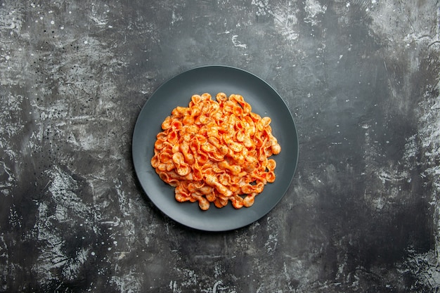 Vista dall'alto di un delizioso pasto di pasta su un piatto nero per cena su sfondo scuro