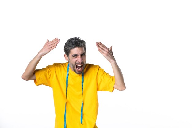 Vista dall'alto di un giovane nervoso in camicia gialla e che tiene il metro su una superficie bianca