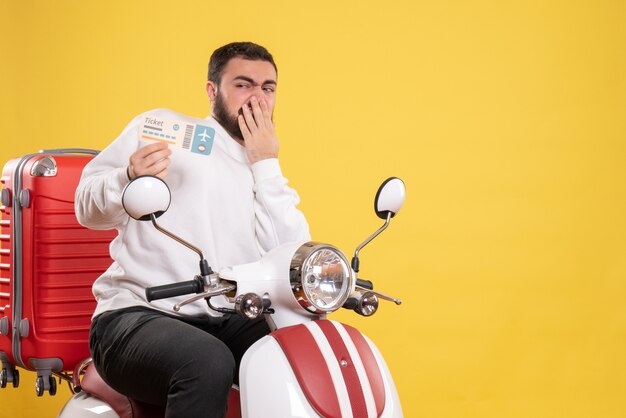 Vista dall'alto di un giovane viaggiatore incerto e incerto seduto su una motocicletta con la valigia sopra che tiene il biglietto giallo