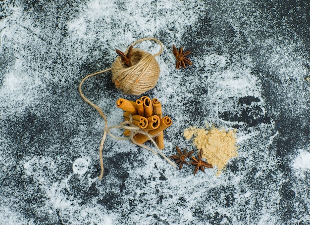 Vista dall'alto di un gomitolo di corda per asciugare la cannella con polvere di zenzero sulla superficie strutturata grigia. orizzontale