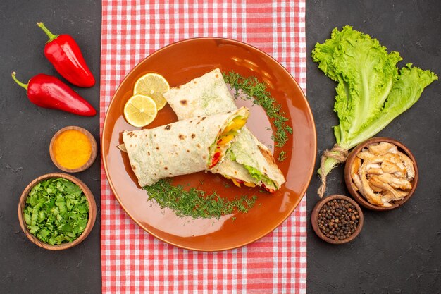 Vista dall'alto di un gustoso panino con insalata di shaurma affettato con verdure e insalata al buio