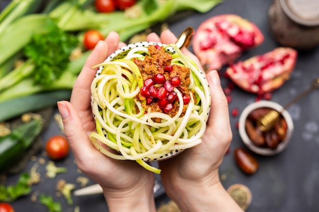 Vista dall'alto di un pasto vegano con zucchine a spirale, salsa di pomodoro e melograni nella tazza