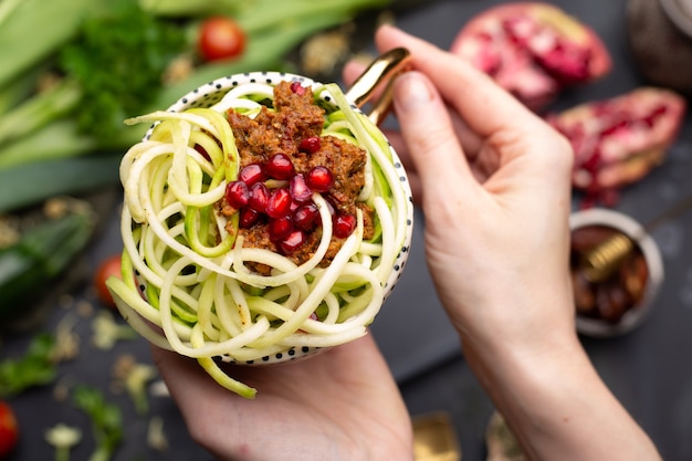 Vista dall'alto di un pasto vegano con zucchine a spirale, salsa di pomodoro e melograni nella tazza