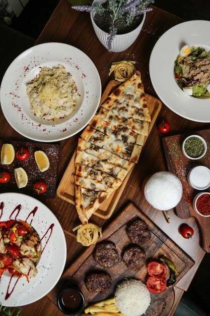Vista dall'alto di un piatto tradizionale turco carne pide con formaggio su un supporto e altri piatti e spezie sul tavolo