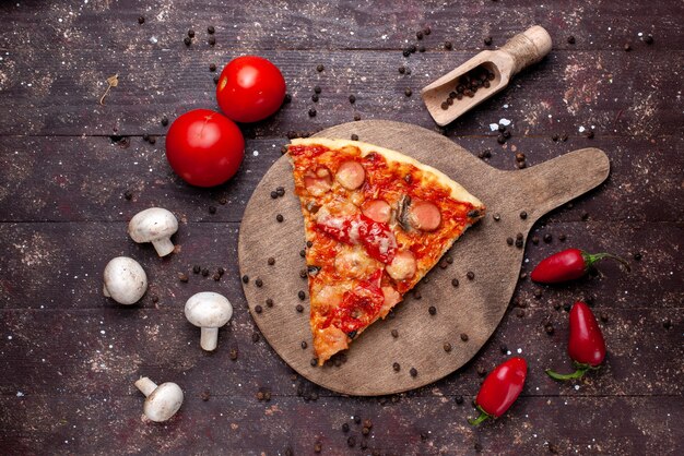 Vista dall'alto di una deliziosa fetta di pizza con funghi freschi pomodori peperoni rossi sullo scrittorio marrone, verdura fast food pasto cibo