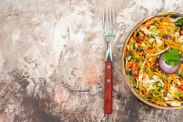 Vista dall'alto di una deliziosa insalata vegana fresca di varie verdure biologiche servite con forchetta