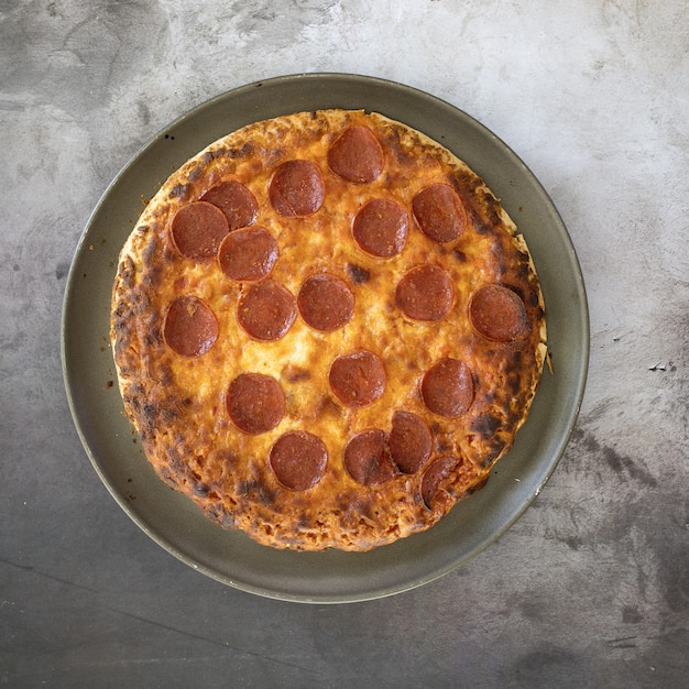 Vista dall'alto di una deliziosa pizza ai peperoni in un piatto sul tavolo sotto le luci