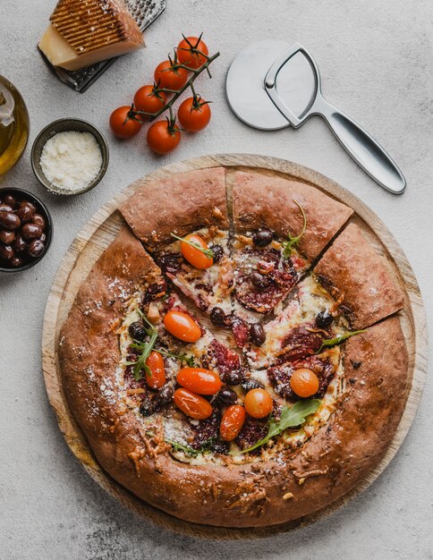 Vista dall'alto di una deliziosa pizza con pomodori e taglierina