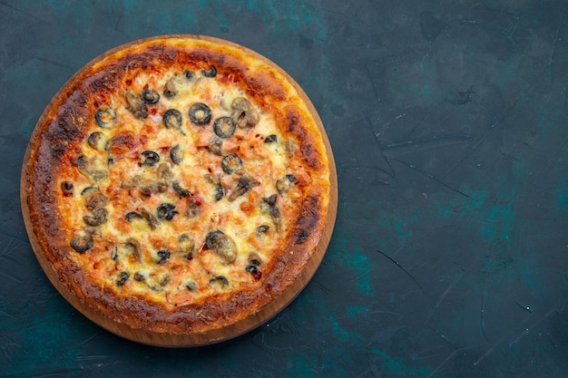 Vista dall'alto di una deliziosa pizza cotta con formaggio e olive sulla scrivania blu scuro