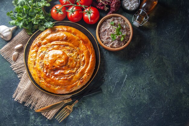 Vista dall'alto di una deliziosa torta di carne con ingredienti su superficie scura