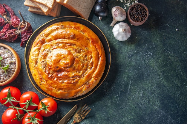 Vista dall'alto di una deliziosa torta di carne con ingredienti su superficie scura