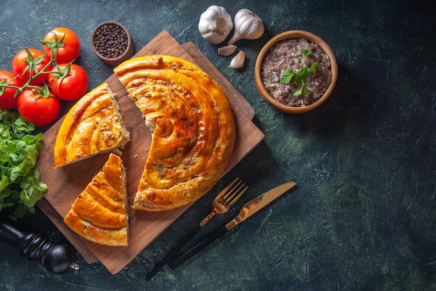 Vista dall'alto di una deliziosa torta di carne con ingredienti su superficie scura