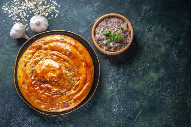 Vista dall'alto di una deliziosa torta di carne con ingredienti su superficie scura