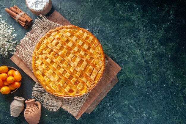 Vista dall'alto di una deliziosa torta di kumquat su una superficie blu scuro