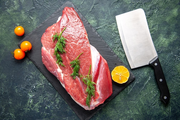 Vista dall'alto di una fetta di limone verde di carne cruda rossa fresca su tagliere e ascia di pomodori su sfondo di colore verde misto nero