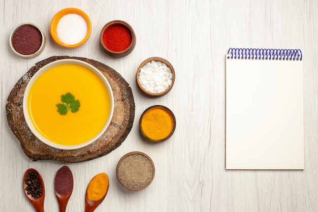 Vista dall'alto di una gustosa zuppa di zucca con diversi condimenti su bianco