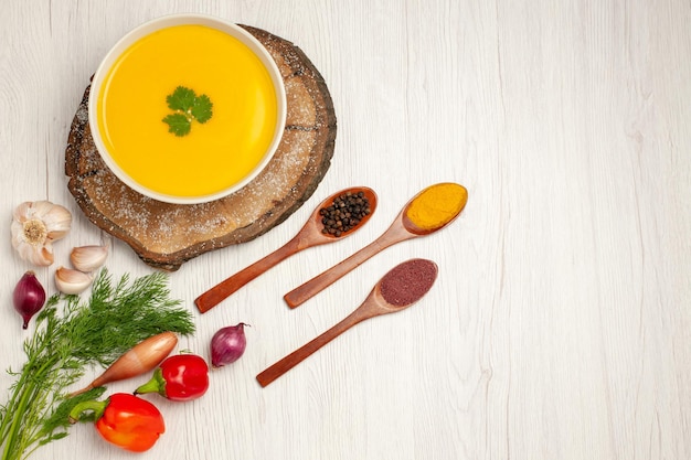 Vista dall'alto di una gustosa zuppa di zucca con verdure su bianco