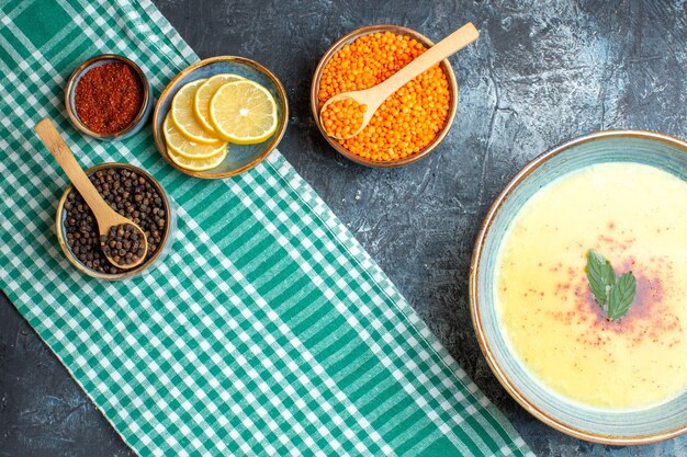 Vista dall'alto di una gustosa zuppa servita con menta e pepe, limone tritato e pisello giallo su sfondo blu