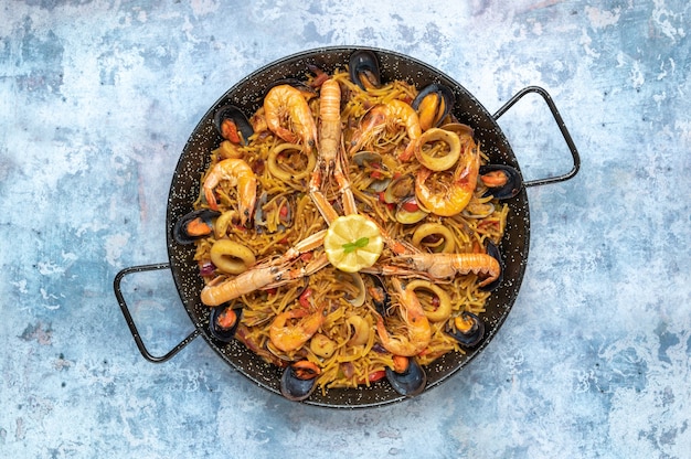 Vista dall'alto di una padella di gustosi frutti di mare e un piatto di pasta