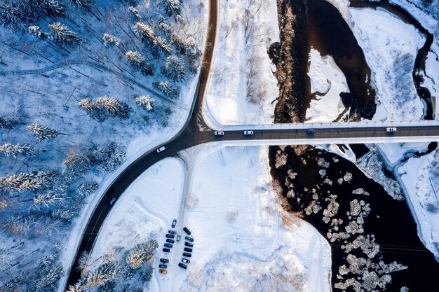 Vista dall'alto di una strada sinuosa su un fiume che scorre attraverso la foresta innevata