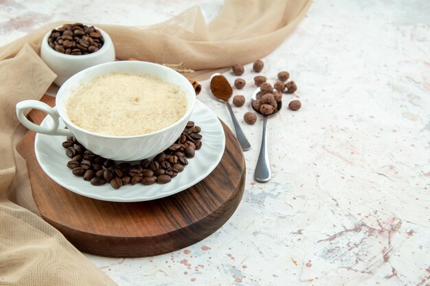 Vista dall'alto di una tazza di caffè e fagioli cannella macinati limes asciugamano di colore nudo sul lato destro su sfondo bianco