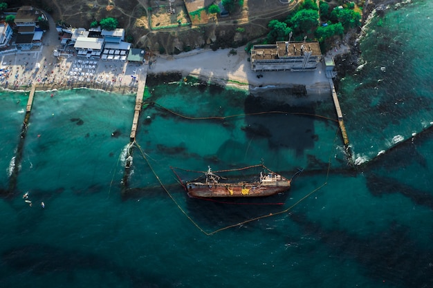 Vista dall'alto di una vecchia petroliera che si è arenata e si è ribaltata sulla riva vicino alla costa.