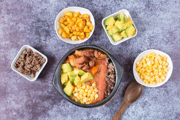 Vista dall'alto di una zuppa con verdure e carne macinata con ingredienti in ciotole separate