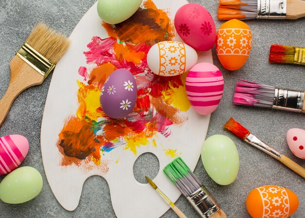 Vista dall'alto di uova di Pasqua colorate con pennelli e tavolozza