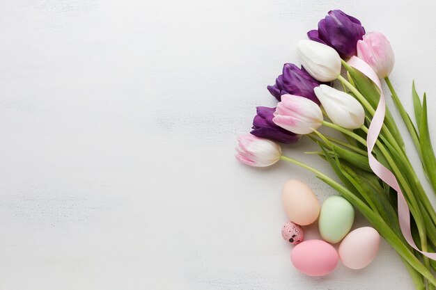 Vista dall'alto di uova di Pasqua con tulipani colorati e copia spazio