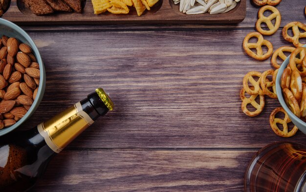 Vista dall'alto di vari spuntini di birra con una bottiglia di birra su rustico con spazio di copia