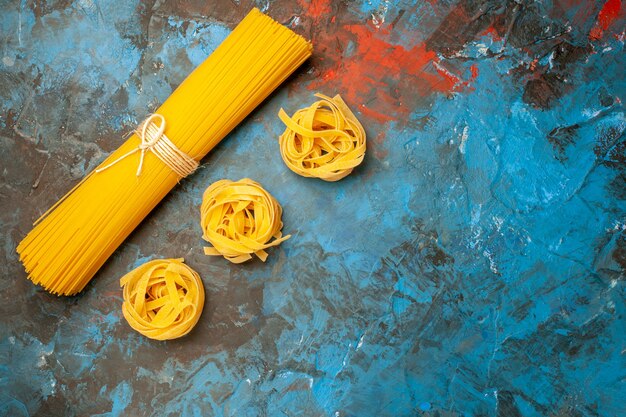 Vista dall'alto di varie paste italiane per la preparazione della cena sul lato destro su sfondo blu