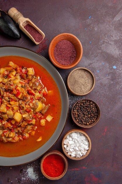 Vista dall'alto di verdure cotte affettate con salsa e condimenti sulla superficie scura salsa pasto cibo cena zuppa di verdure