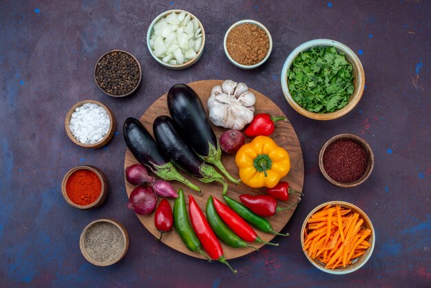 Vista dall'alto di verdure e condimenti con cipolle affettate e verdure fresche sullo spuntino di verdure del pasto dell'insalata della scrivania scura