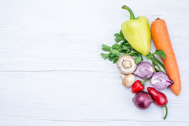 Vista dall'alto di verdure fresche come carote, cipolle verdi e peperone verde sulla scrivania leggera, vitamina pasto vegetale