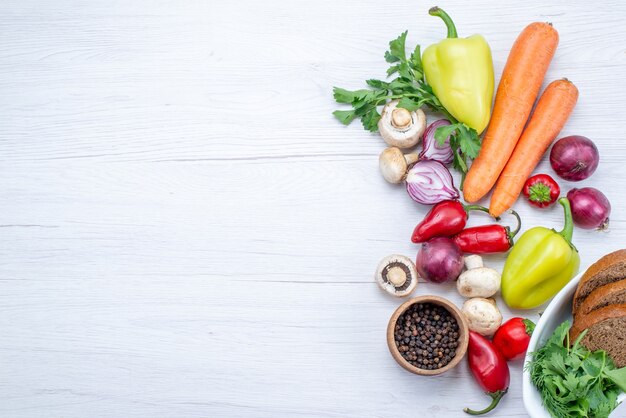 Vista dall'alto di verdure fresche come cipolle carote pepe con pane sulla scrivania leggera, vitamina pasto di cibo vegetale