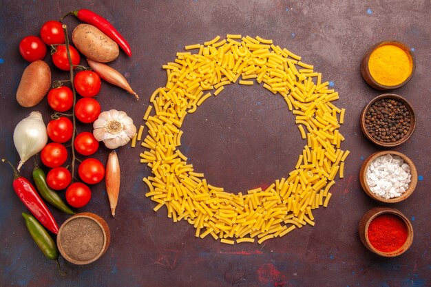 Vista dall'alto di verdure fresche con diversi condimenti e pasta nello spazio buio