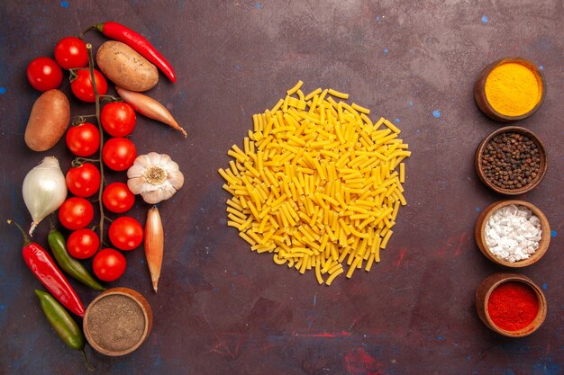 Vista dall'alto di verdure fresche con diversi condimenti e pasta nello spazio buio