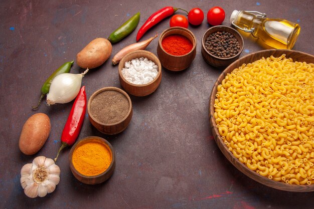 Vista dall'alto di verdure fresche con diversi condimenti e pasta nello spazio buio