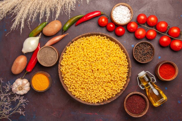 Vista dall'alto di verdure fresche con diversi condimenti e pasta su una scrivania scura