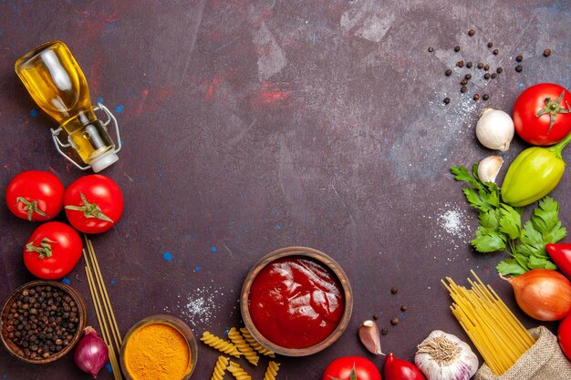 Vista dall'alto di verdure fresche con olio e pasta cruda su nero