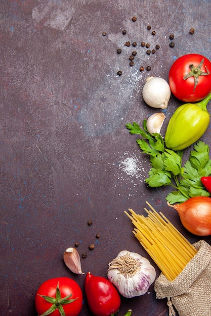 Vista dall'alto di verdure fresche con pasta cruda su nero