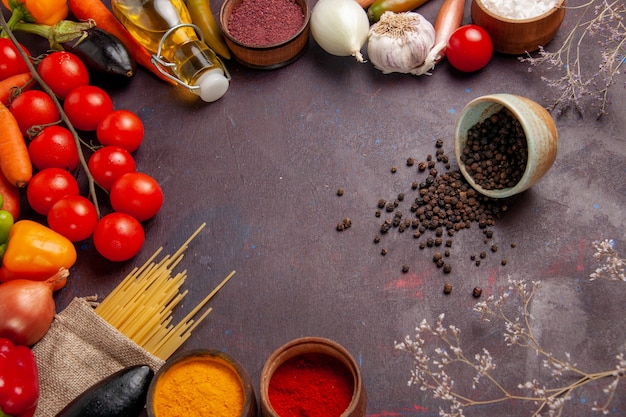 Vista dall'alto di verdure fresche con pasta italiana cruda e condimenti sulla scrivania scura