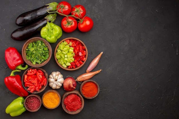 Vista dall'alto di verdure fresche con verdure e condimenti diversi sulla verdura di cibo salutare insalata di pasto scrivania grigia