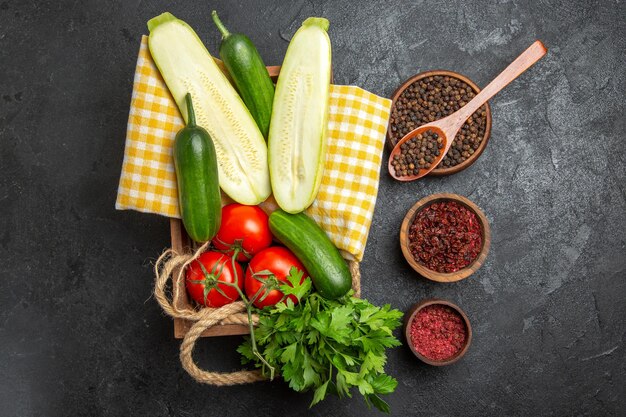 Vista dall'alto di verdure fresche pomodori rossi cetrioli e zucche con verdure sulla superficie grigia