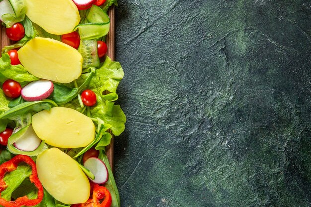 Vista dall'alto di verdure fresche tritate su un vassoio di legno sul lato destro su sfondo di colori della miscela con spazio libero