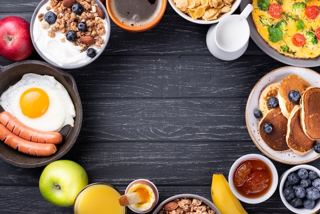 Vista dall'alto di yogurt e cereali con uova e salsicce per la colazione