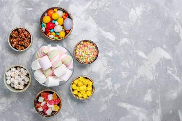 Vista dall'alto diverse caramelle colorate con marmellata sulla scrivania bianca