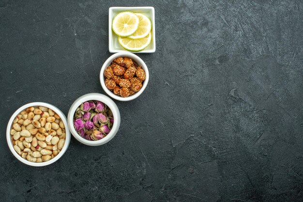 Vista dall'alto diverse noci con limone e caramelle su uno spuntino di noci con superficie scura dolce