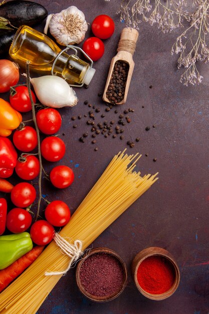 Vista dall'alto diverse verdure fresche con pasta italiana e condimenti nello spazio buio